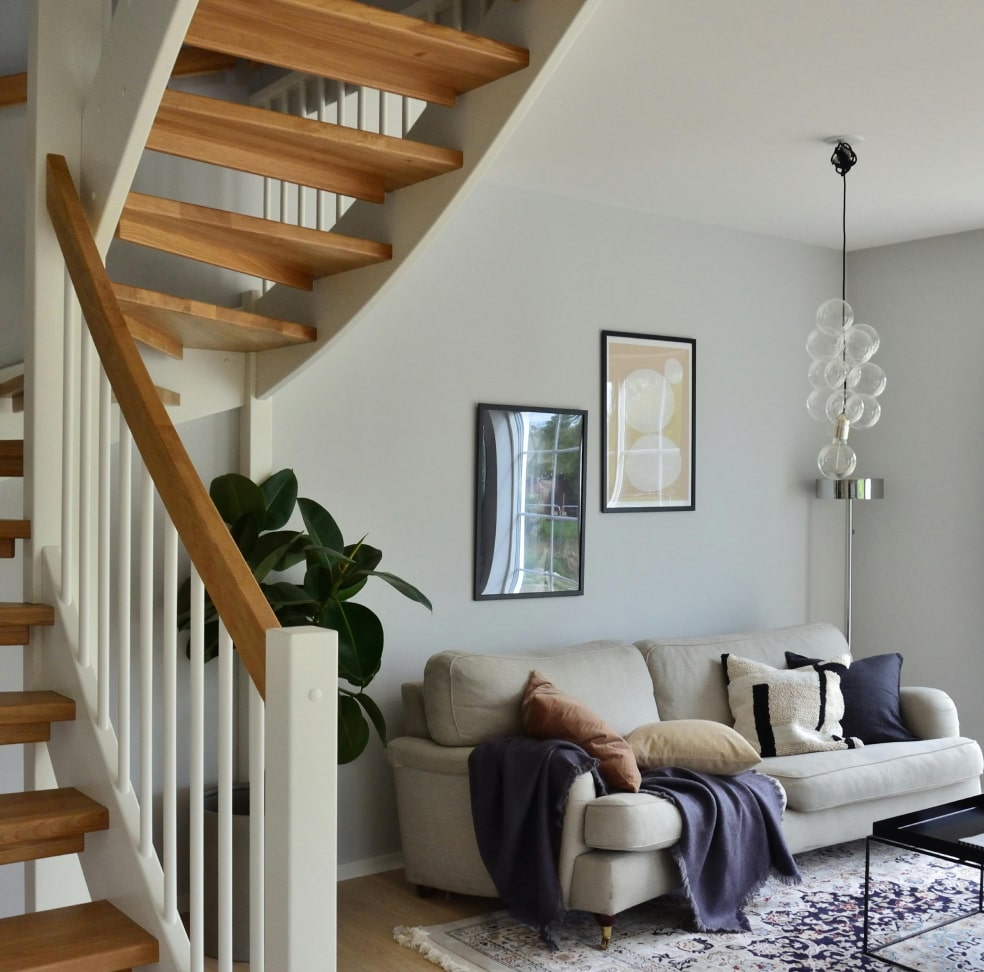 Spacious modern living room with vaulted ceilings, exposed wooden beams, and a sleek metal staircase leading to a mezzanine loft. The open-plan design includes a minimalist fireplace, floor-to-ceiling glass walls, and a seamless connection to outdoor spaces. Ideal for contemporary architecture and luxury loft-style interiors.
